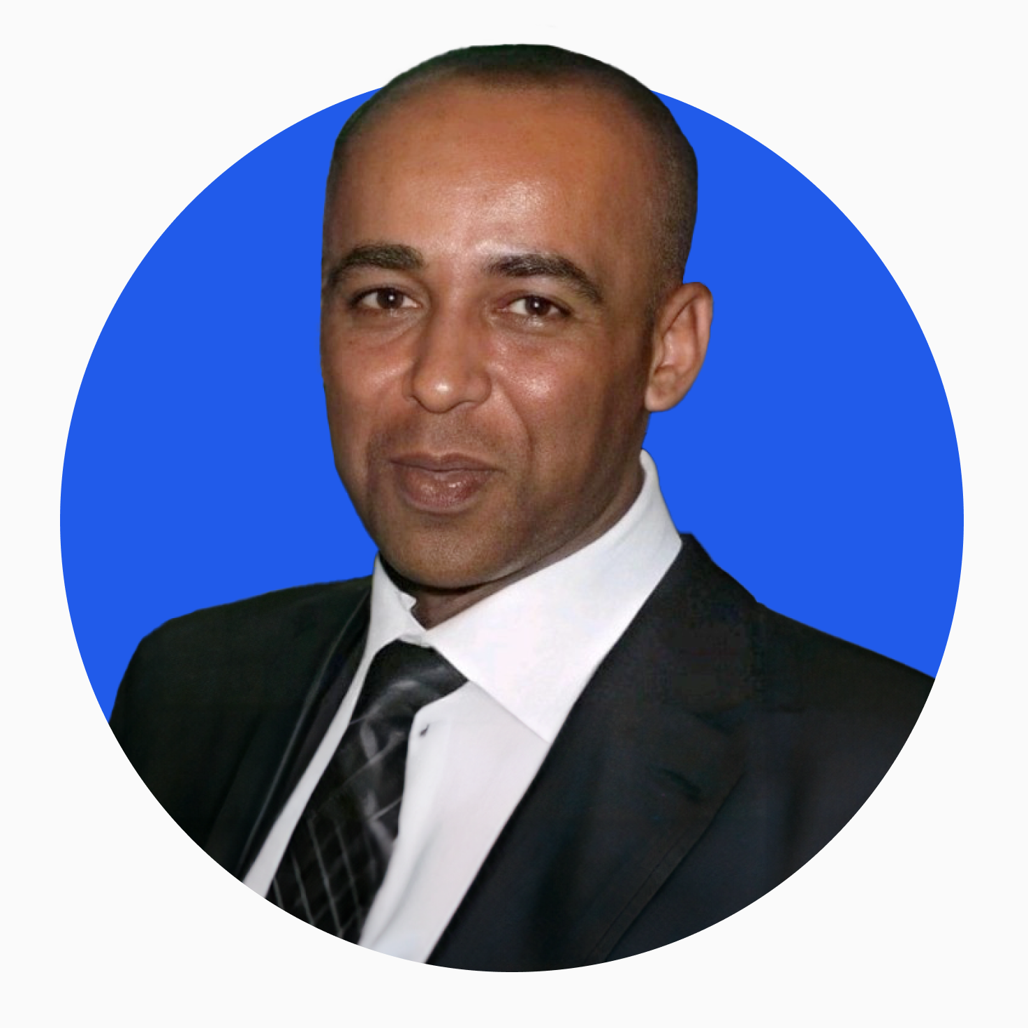 Portrait of a man in a black suit, white shirt, and patterned black tie with a blue circular background.