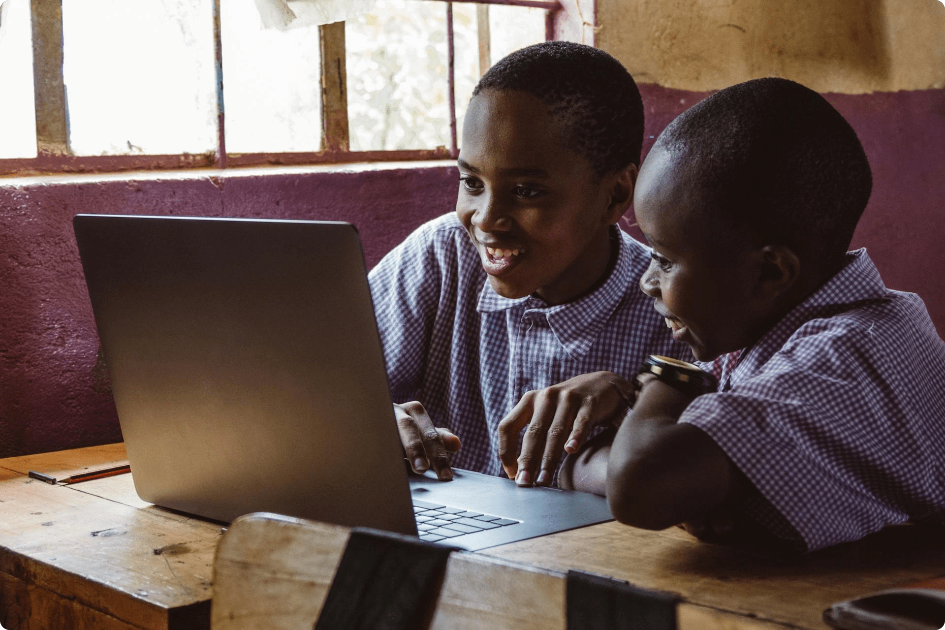 Two boys sitting in front of a laptop at school. 