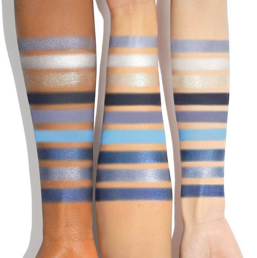 Blue eyeshadow palette swatches on an arm.