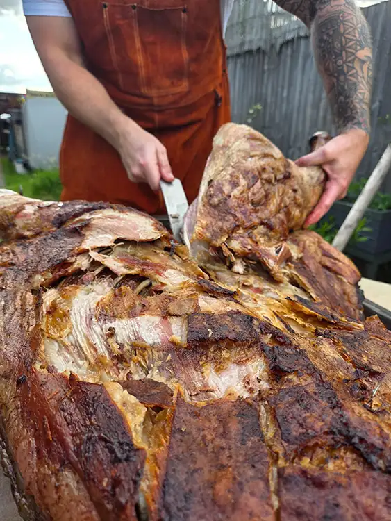 BBQ flame cooked lamb being cut and portioned 