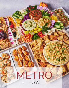 Assorted Metro Catering spread with dips, crudités, flatbread, pastries, skewers, and bite-sized appetizers arranged on white catering trays.