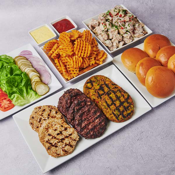 Build-your-own mini slider catering package with grilled chicken, beef, and veggie patties, brioche buns, lettuce, tomato, pickles, red onion, waffle fries, dipping sauces, and potato salad.