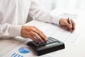 Person using a calculator to review the NDIS Price Guide for service rates and support cost limits.