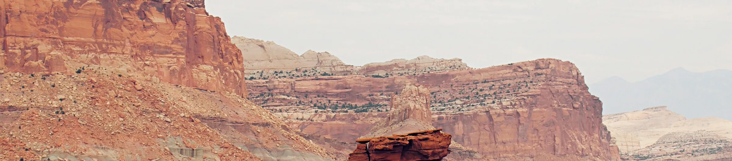 Panoramic view of red sandstone mesas, eroded cliffs, and distant desert mountains in the Capitol Reef region near Torrey, Utah.