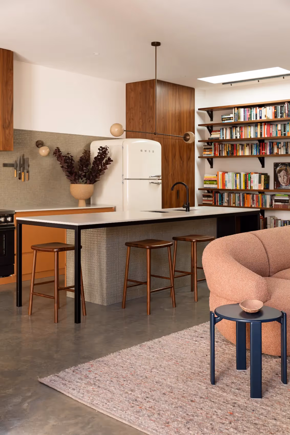 Open-plan kitchen and living area with a library wall in an architectural home in Melbourne.