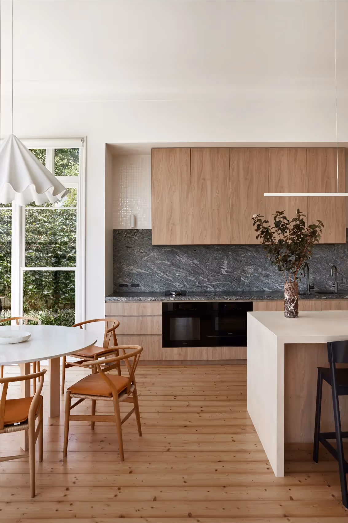 Kitchen and dining space with timber cabinetry in an architectural home in Melbourne.