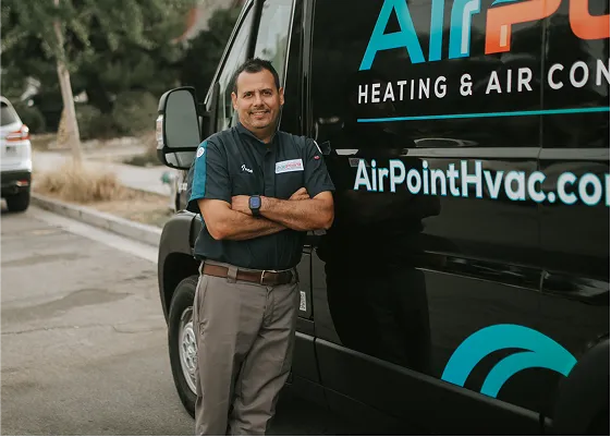 HVAC technician standing next to company van in parking lot