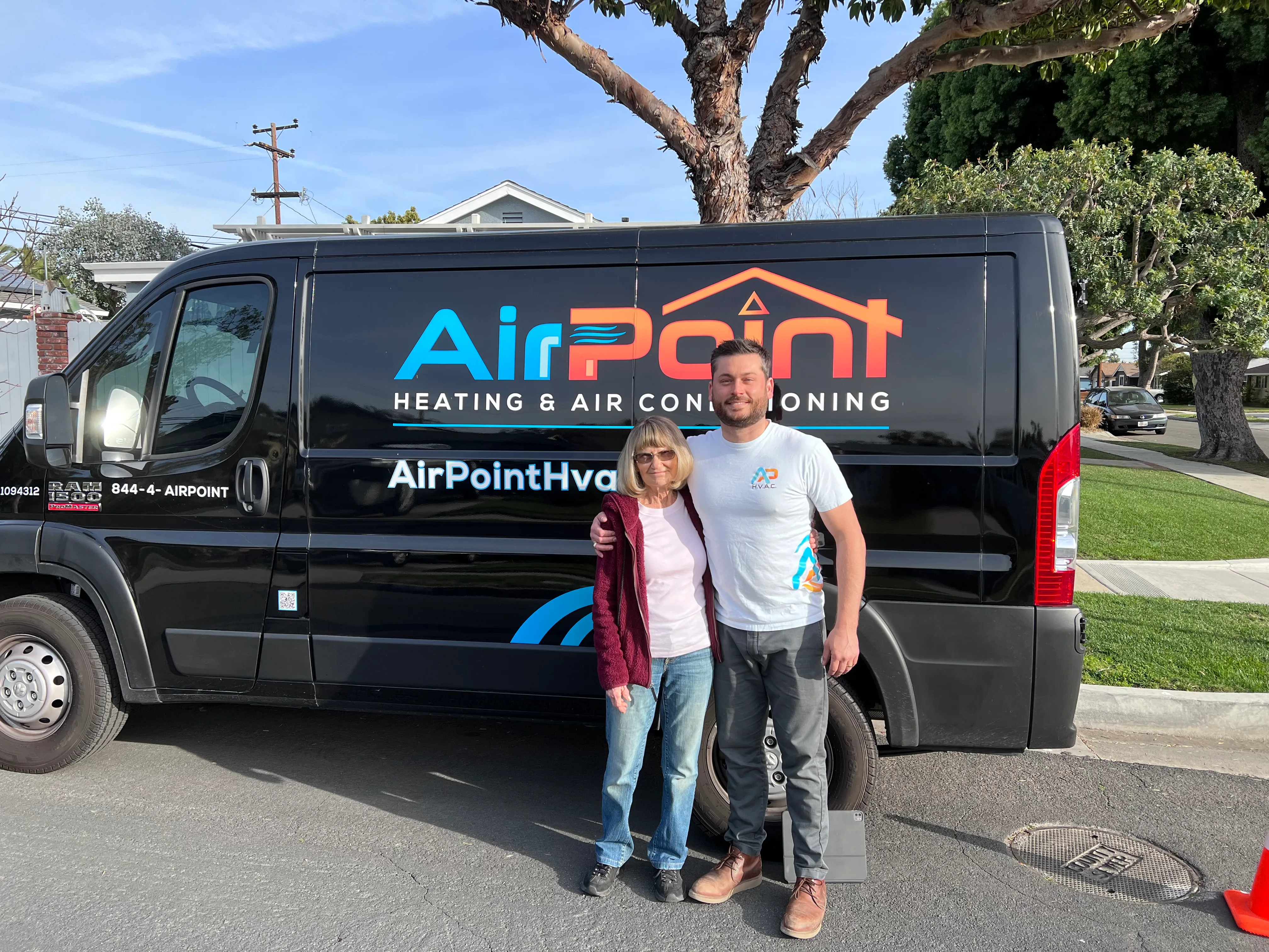 Two people standing next to an AirPoint Heating & Air Conditioning van