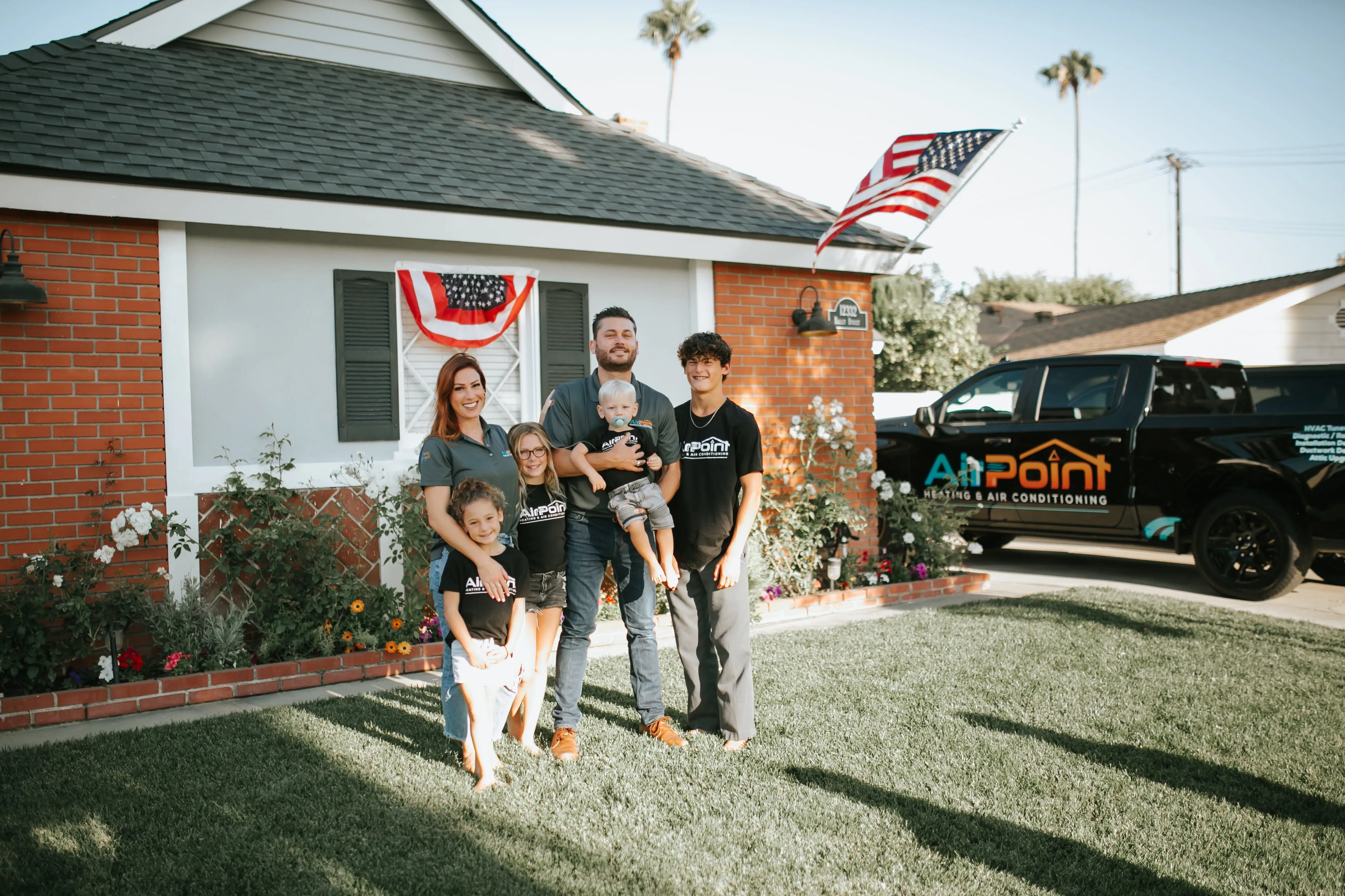 Family posing in front of their home with Air Point truck and American flag