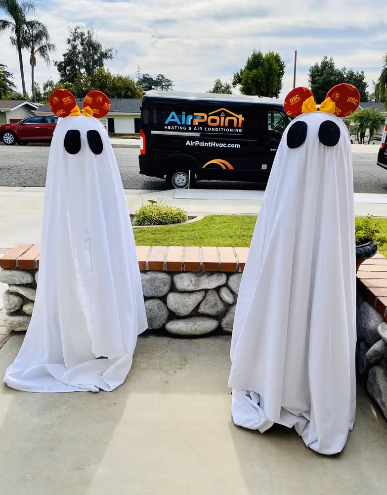 “Two ghost decorations in front of AirPoint service van during Halloween.”