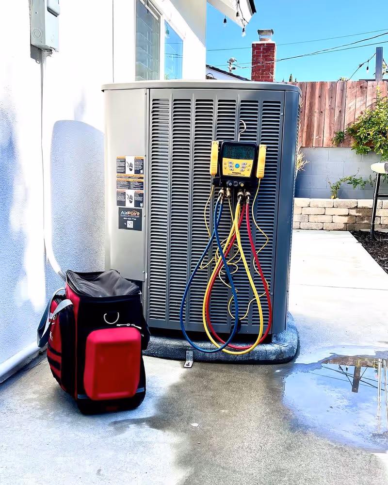 “Outdoor AC unit with diagnostic gauges and tool bag during AirPoint HVAC tune-up.”
