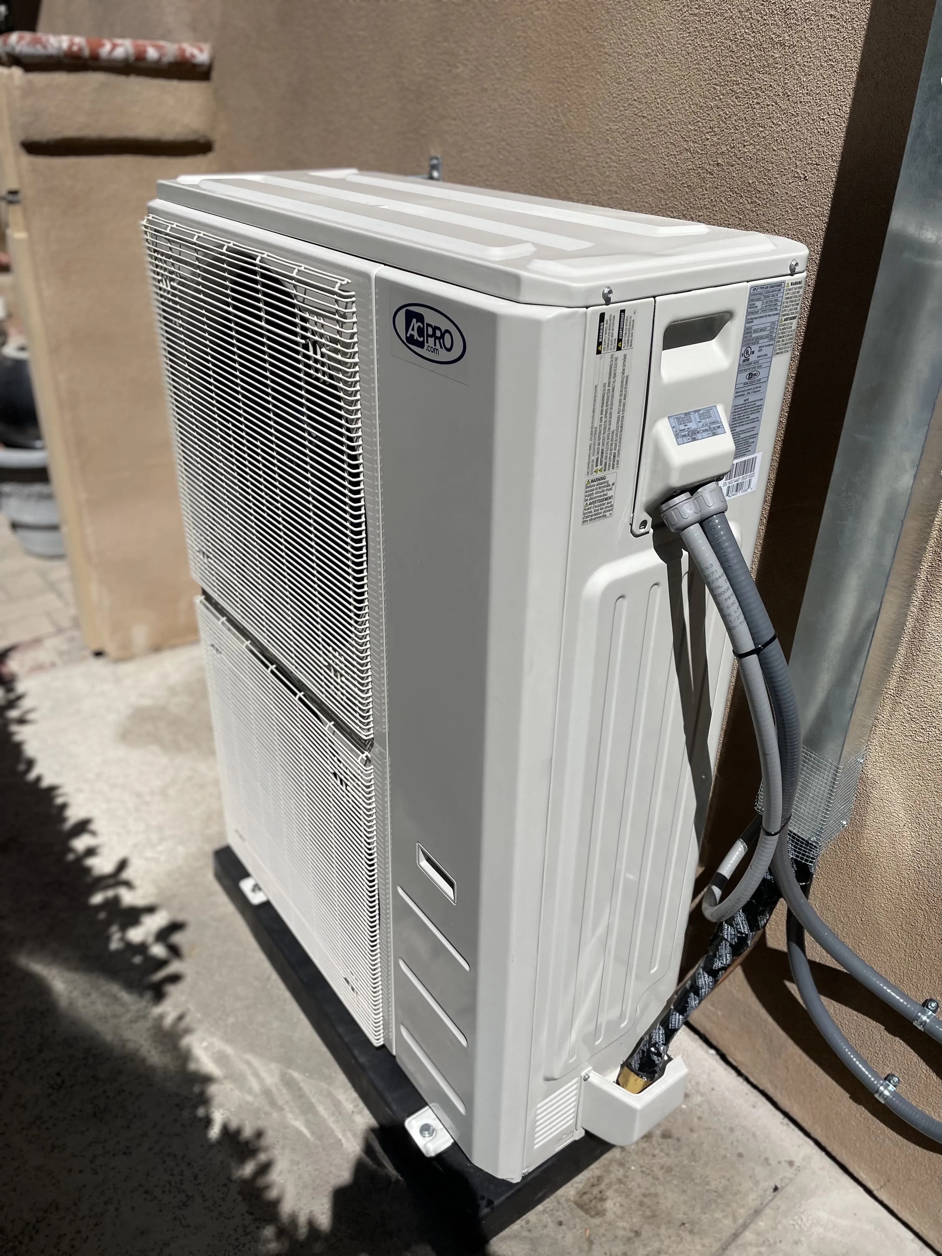 White outdoor air conditioning unit mounted on beige wall