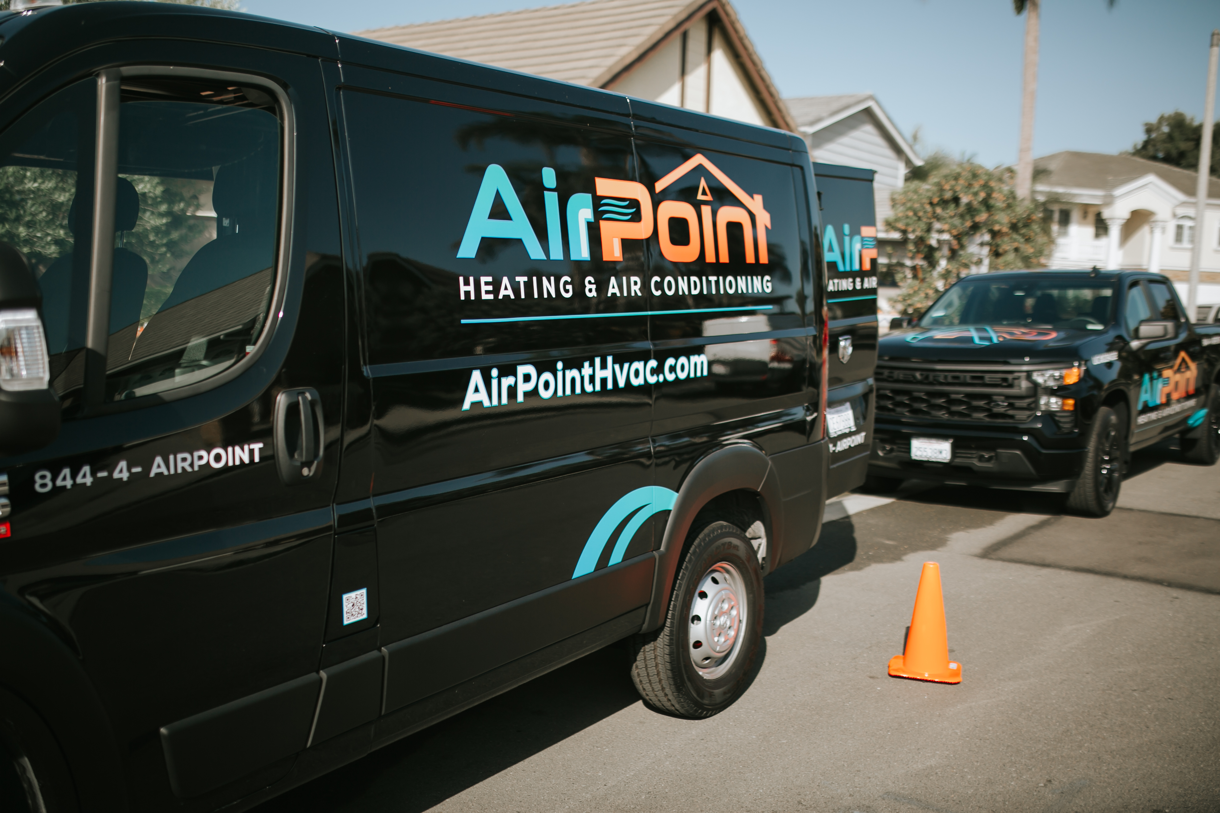 Black AirPoint Heating & Air Conditioning van parked with orange cone