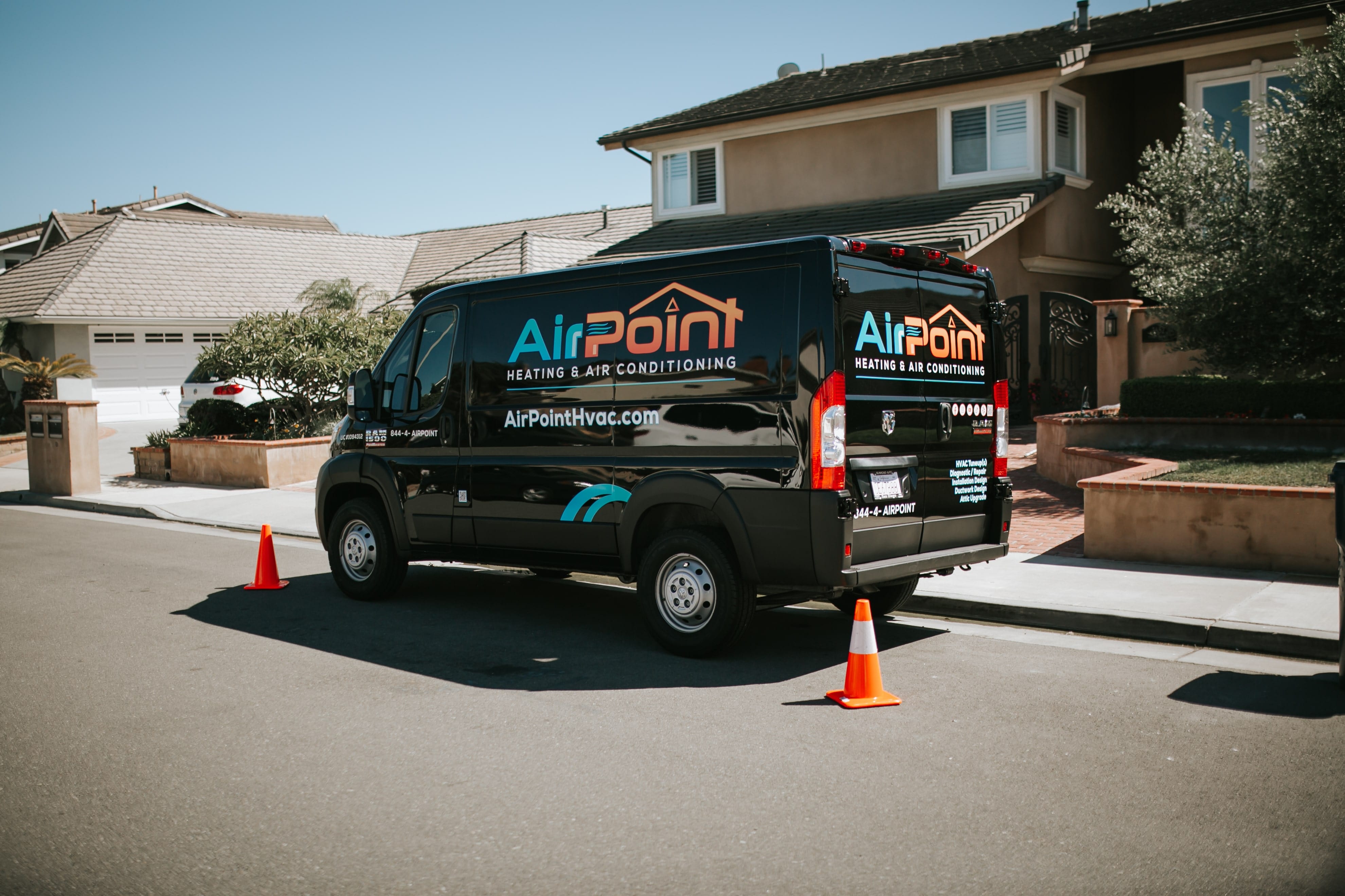 Black AirPoint HVAC van parked on residential street with traffic cones