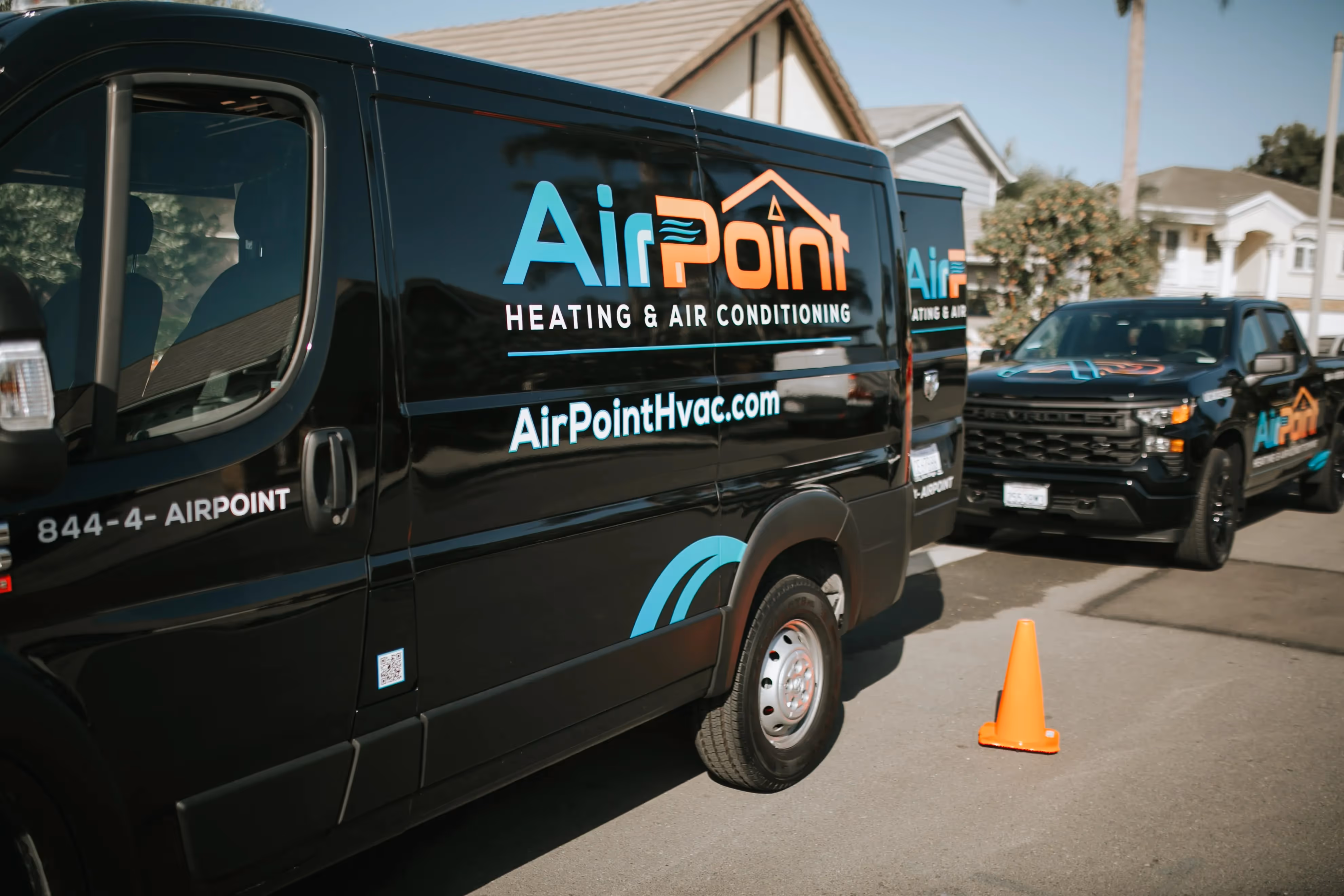 Black AirPoint HVAC service van parked on street with orange traffic cone