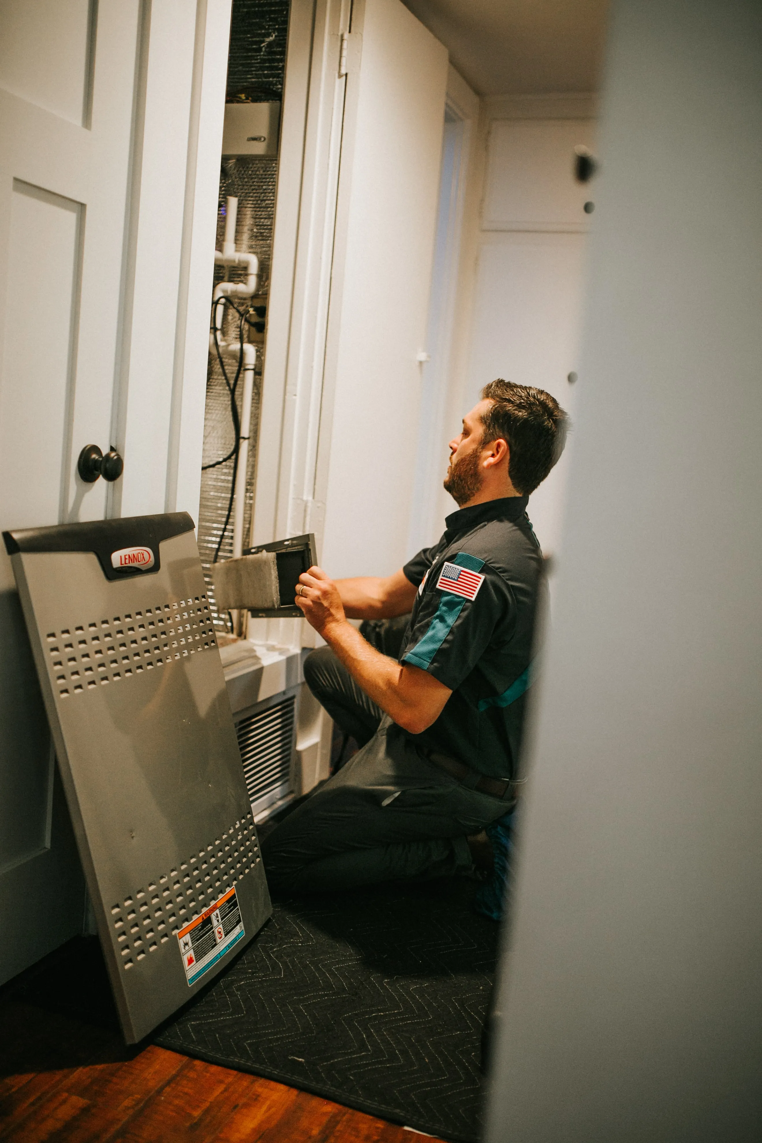 Technician checking HVAC system in utility closet with Lennox equipment