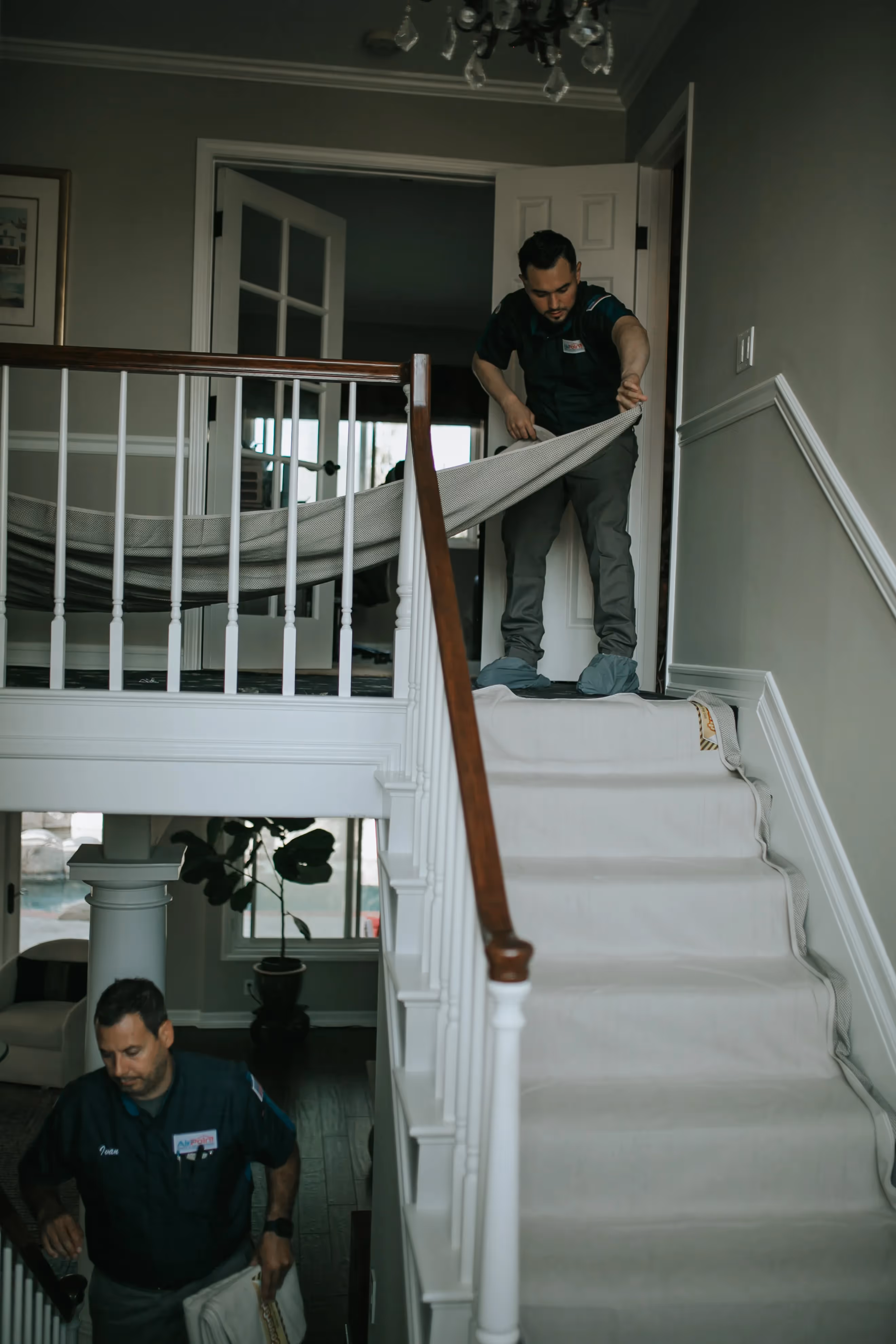 Workers installing carpet on stairs in a residential home interior
