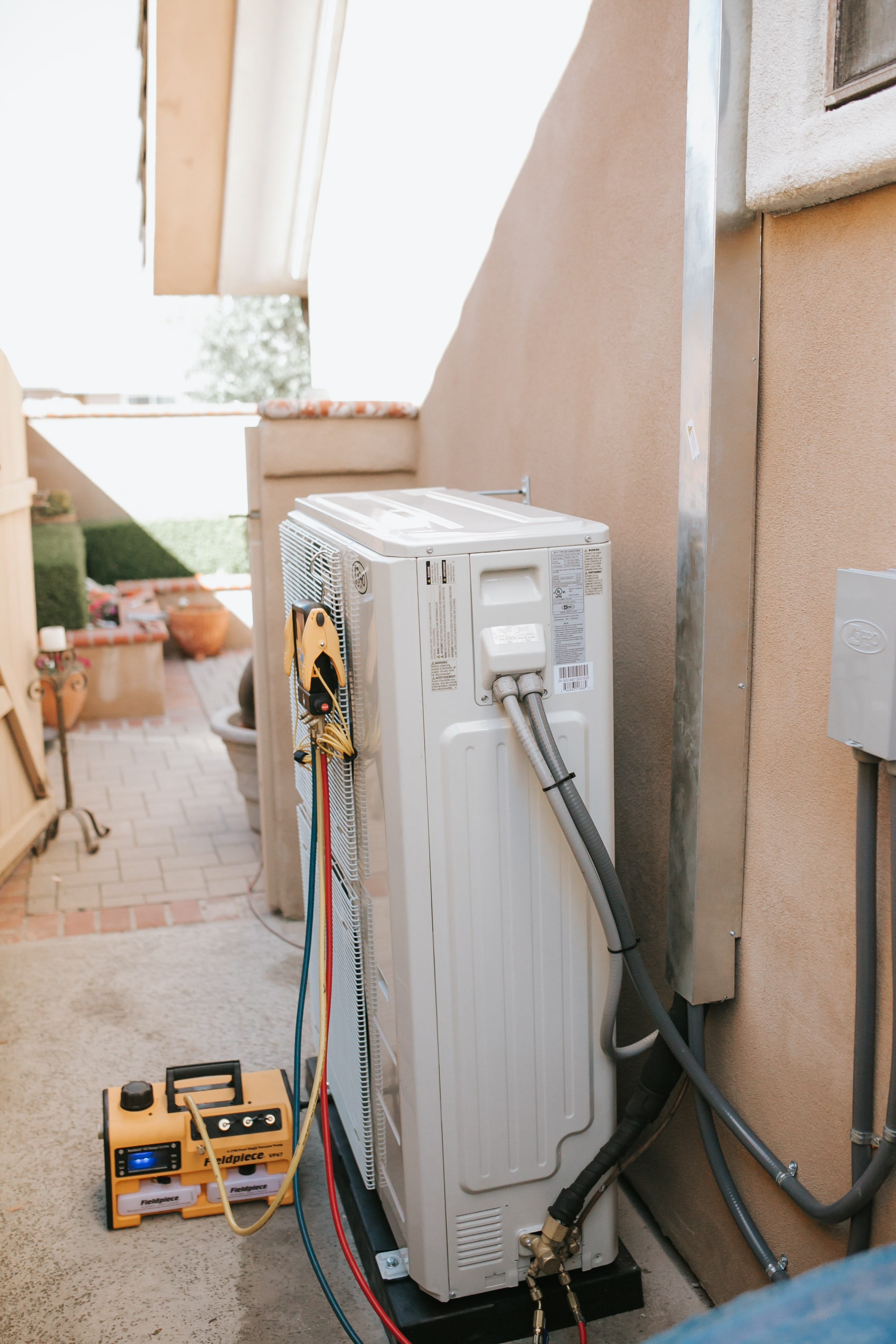 White air conditioner unit with yellow diagnostic tool on outdoor patio