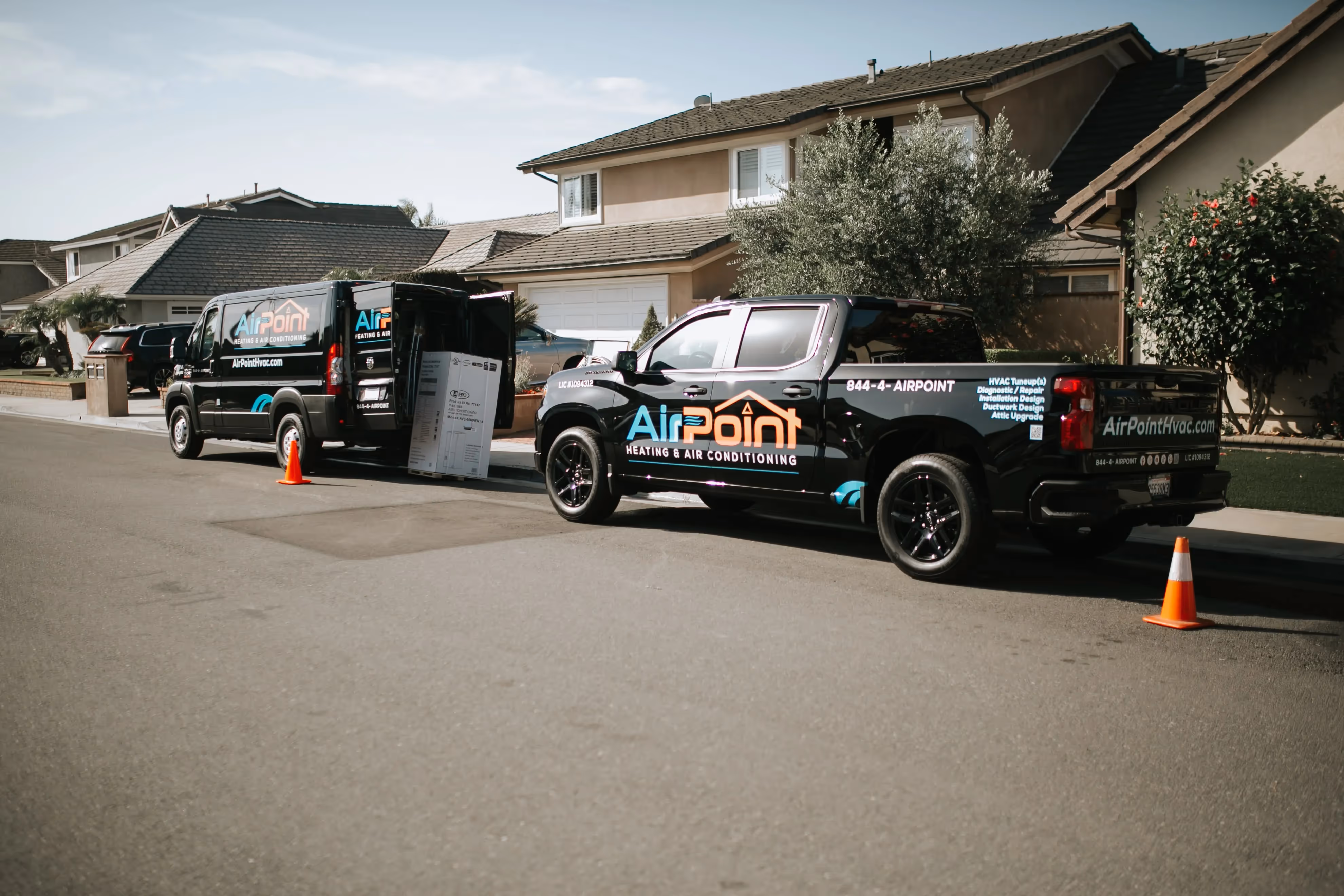 AirPoint HVAC service vehicles parked on suburban street with orange cones