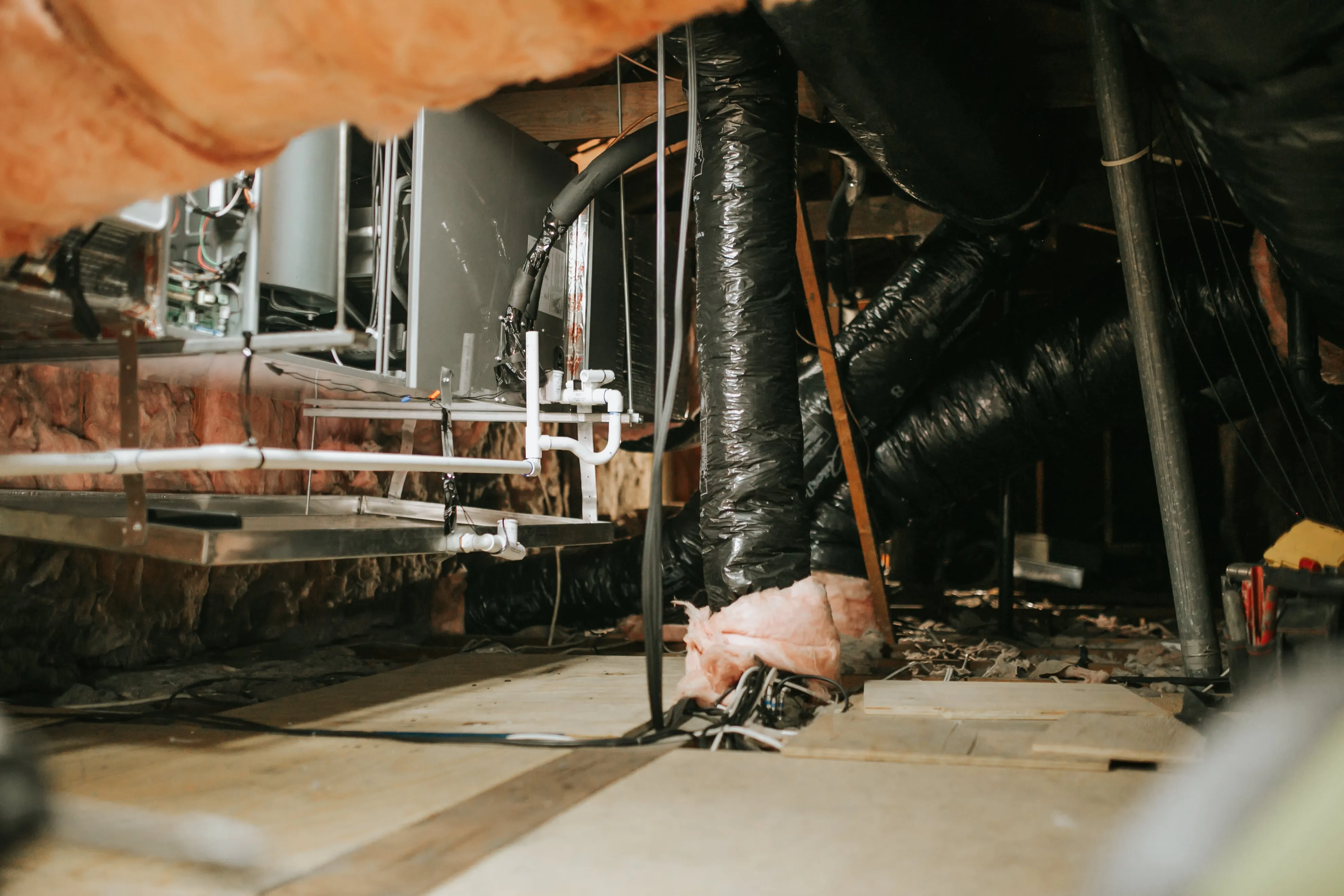 Crawl space with exposed pipes, insulation, and mechanical equipment