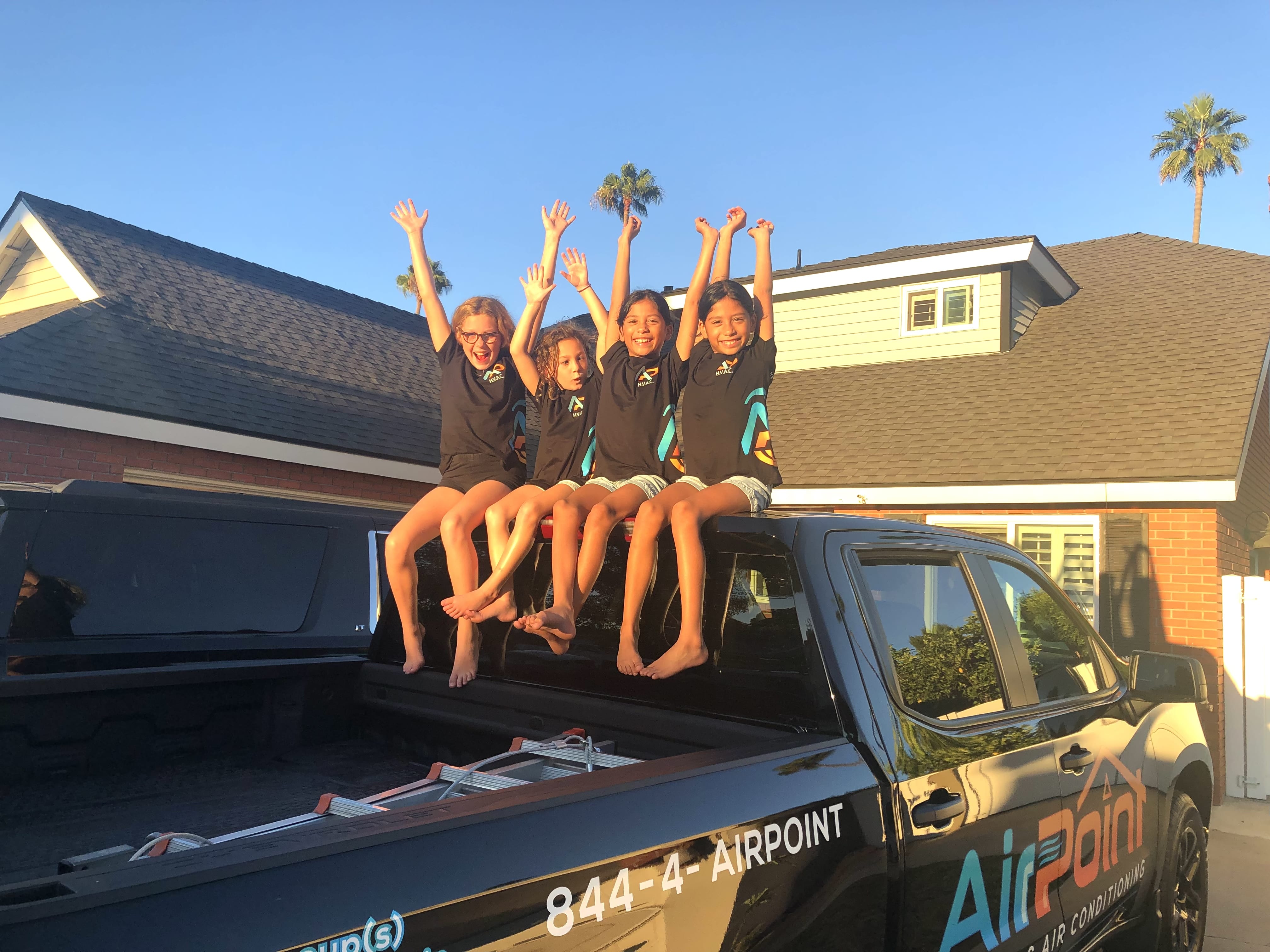 Four excited children sitting on Airpoint truck raising hands