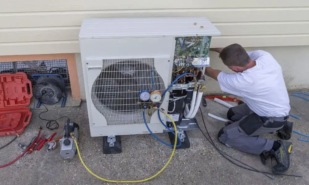 Technician repairing an air conditioning unit with tools and gauges