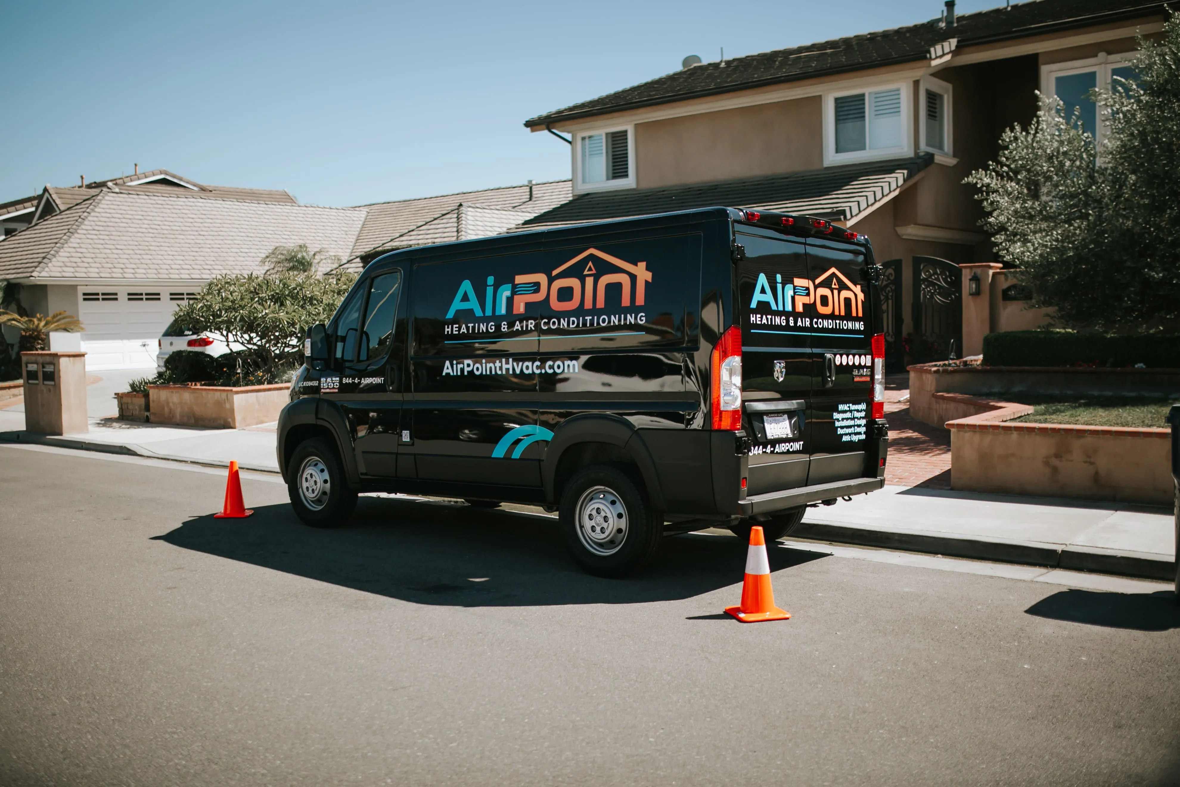 Black AirPoint HVAC van parked on residential street with traffic cones