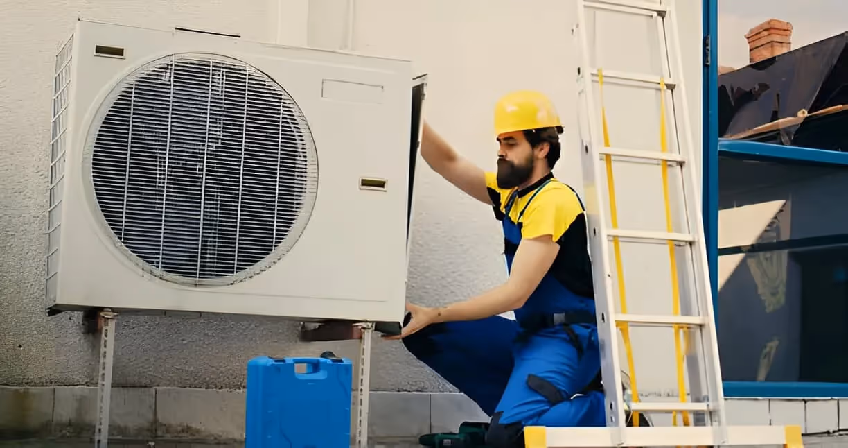 Technician in safety gear installing or repairing an air conditioning unit