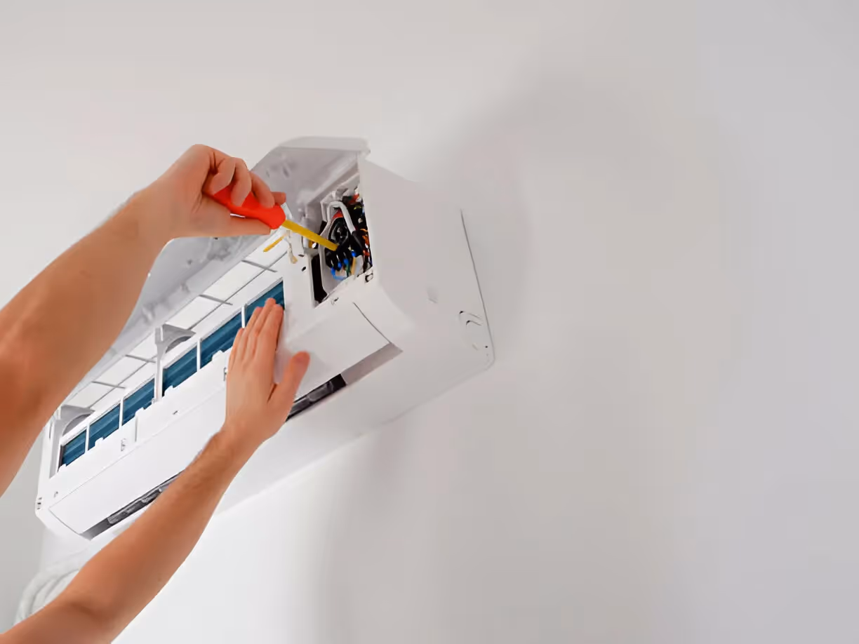 Electrician installing wires in a wall-mounted air conditioning unit