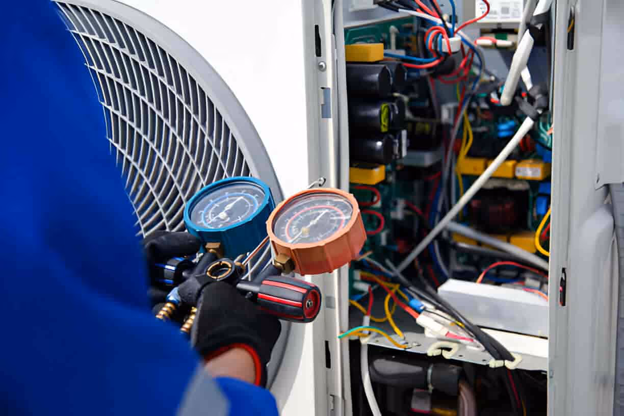 Technician checking pressure gauges inside electrical equipment cabinet