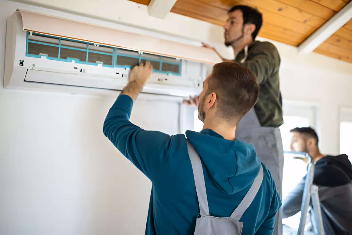 Technicians installing air conditioning unit on wooden-ceiling wall