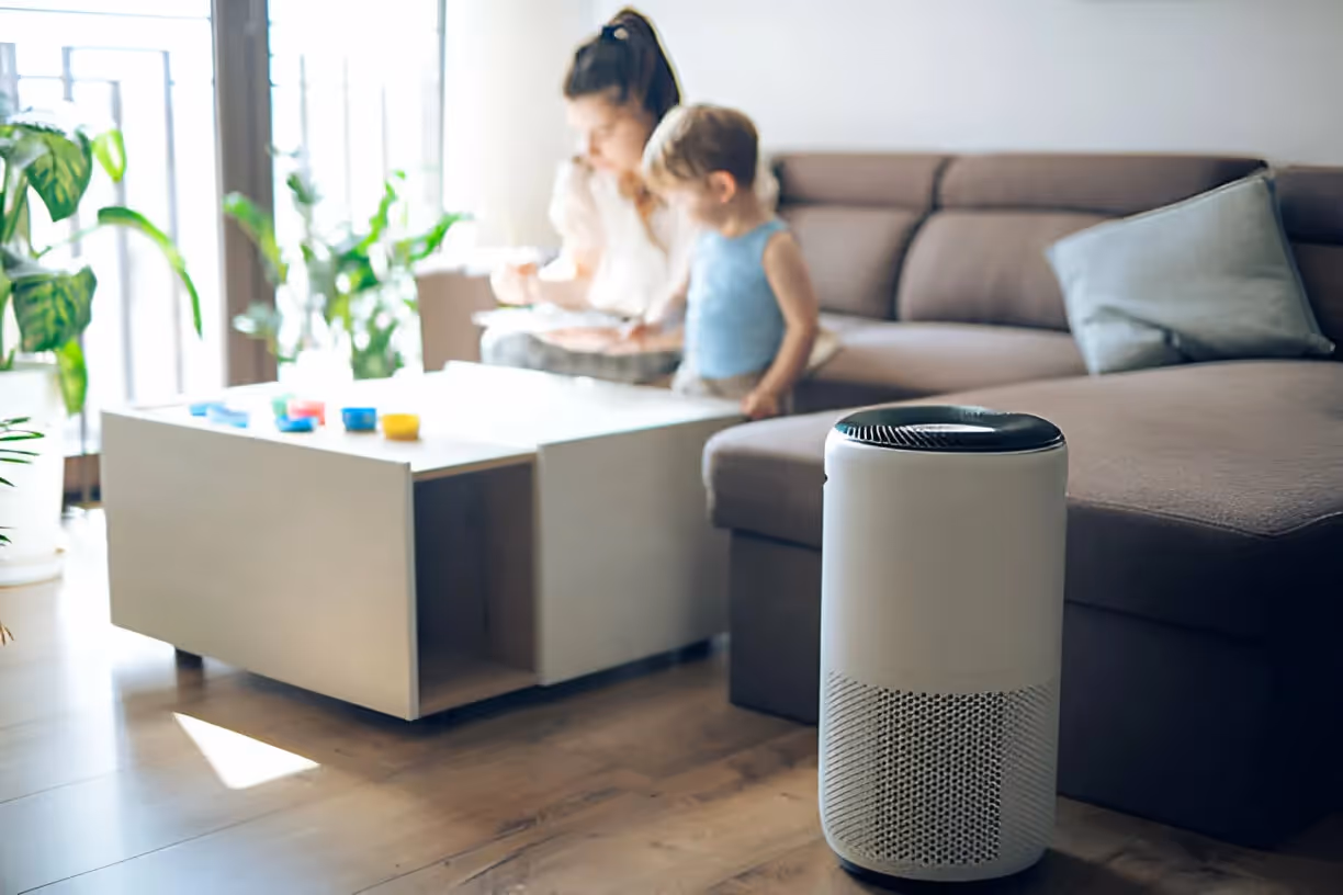 Air purifier in living room with caregiver and child playing nearby