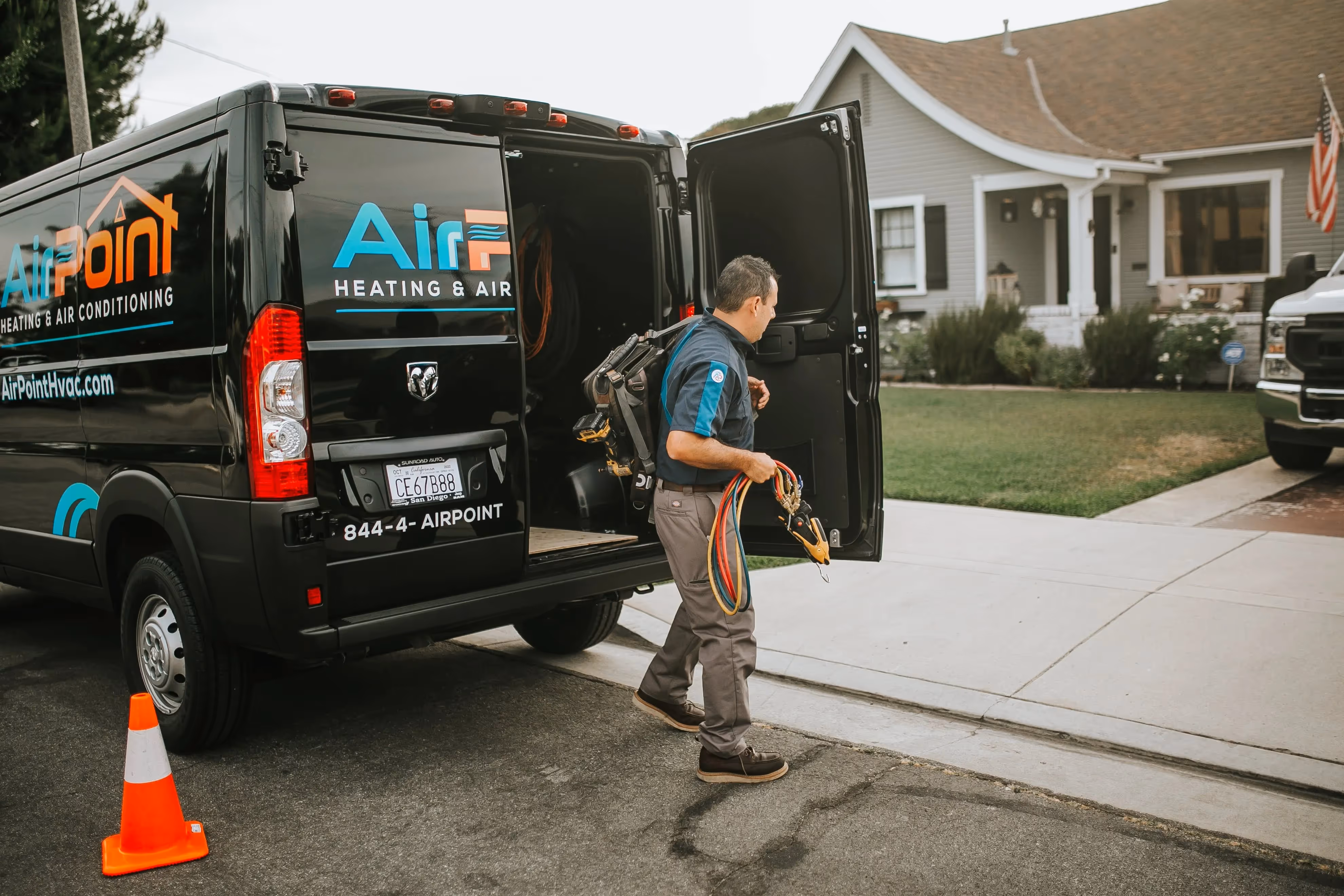 HVAC technician with equipment loading van in residential neighborhood