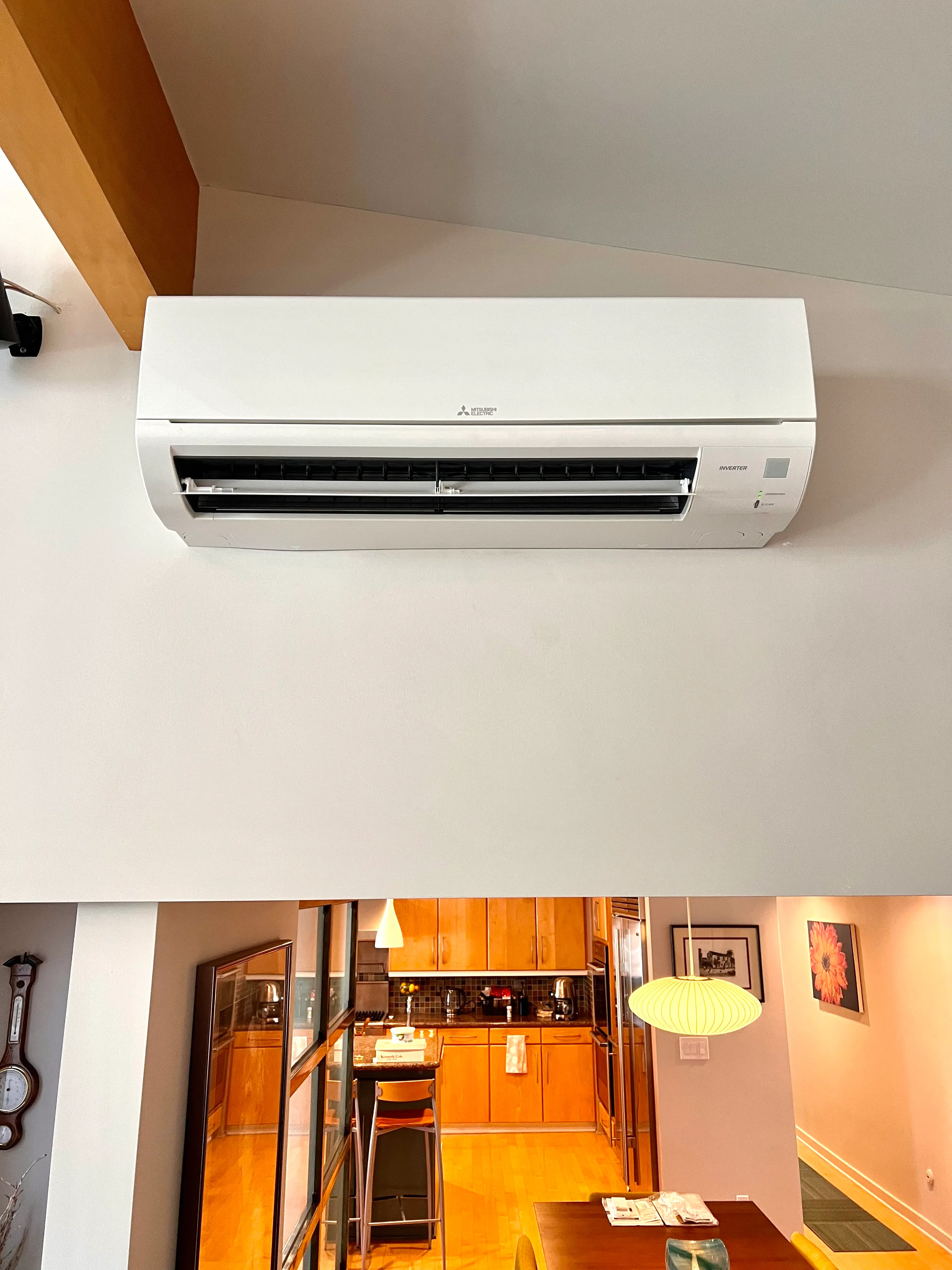 White Mitsubishi air conditioning unit mounted on wall above kitchen