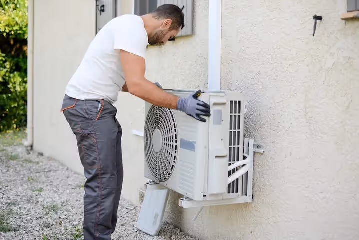 Technician installing or repairing an outdoor air conditioning unit