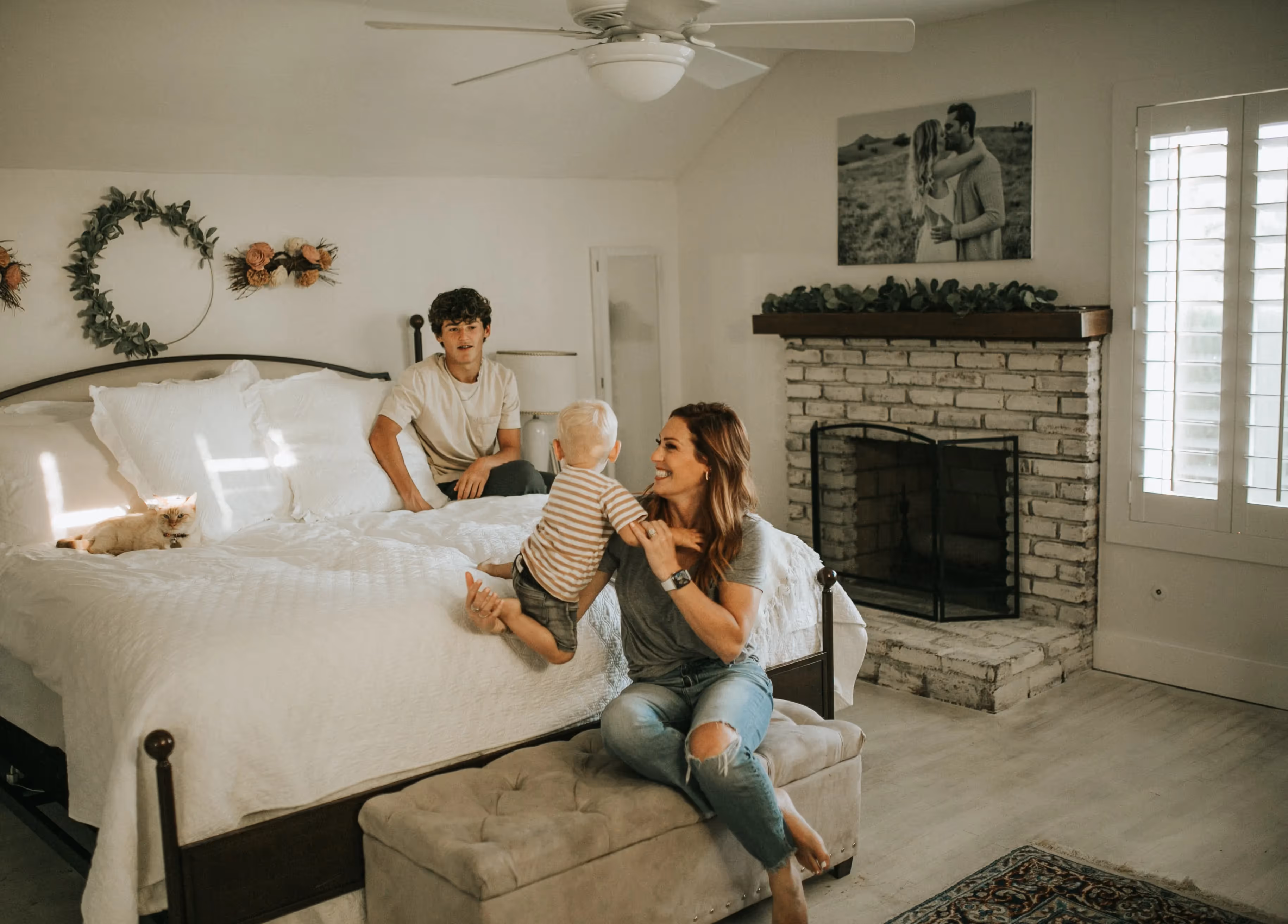 Family relaxing together in cozy bedroom with white bed and fireplace