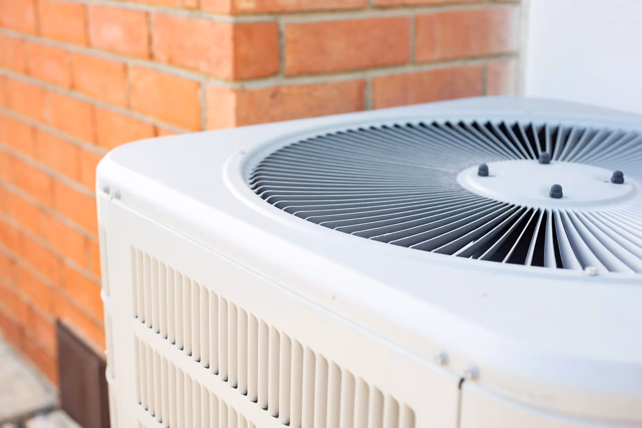Air conditioning unit outside brick building with fan and vents