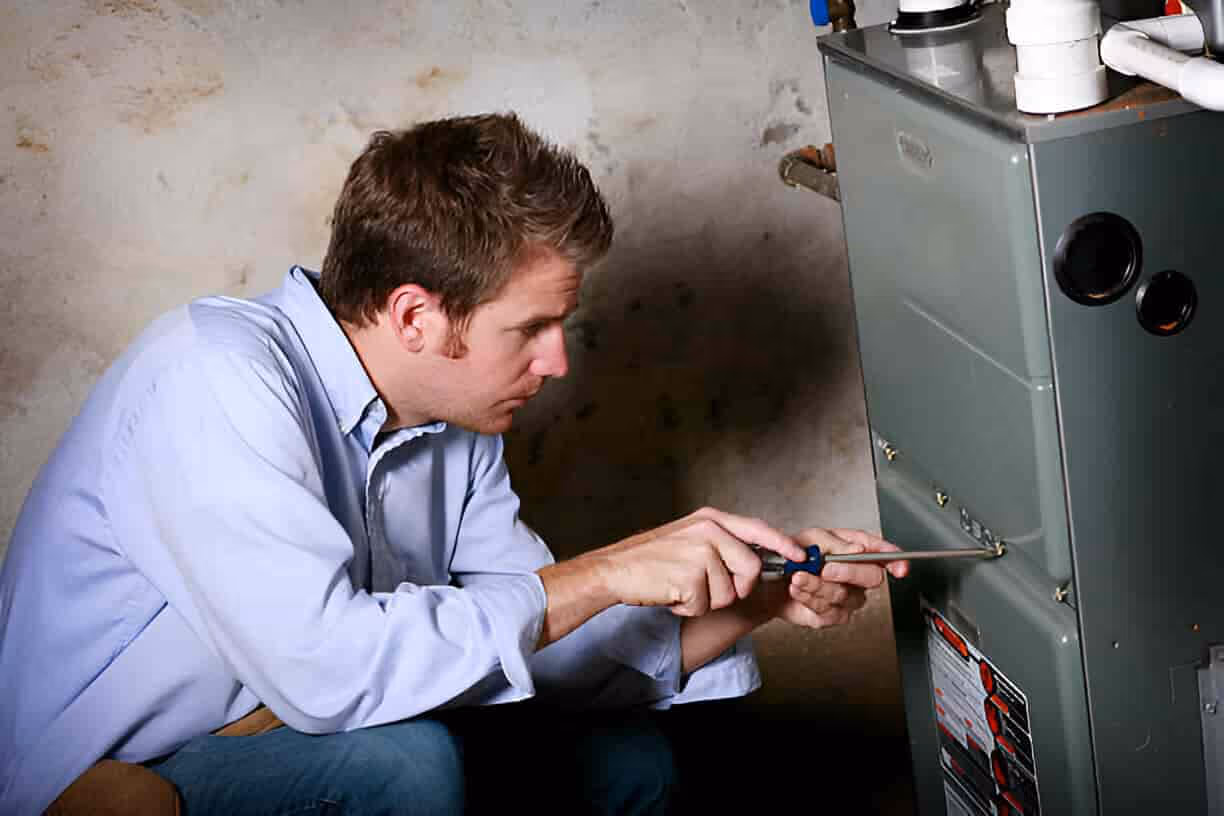 Technician repairing heating system or electrical panel with screwdriver