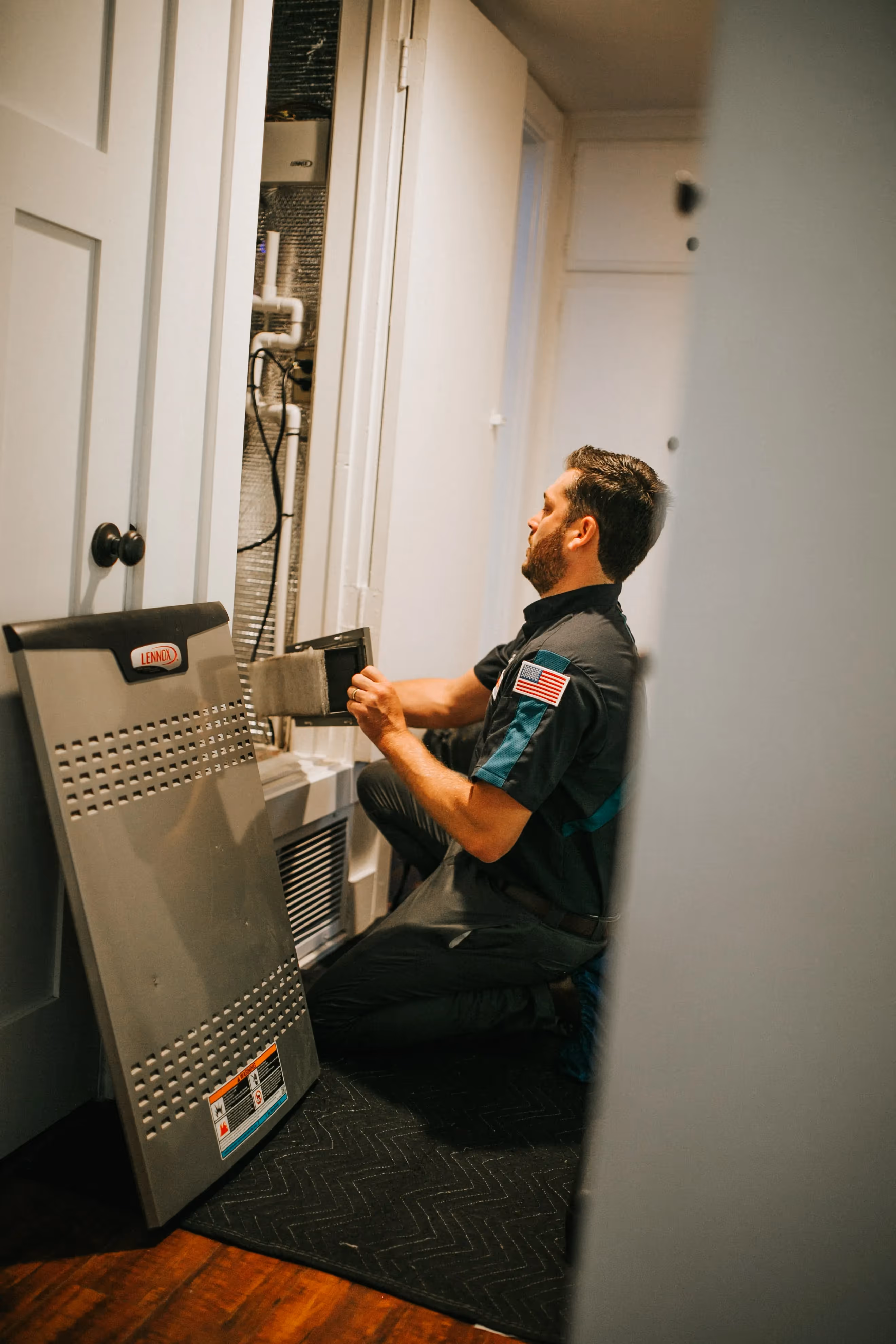 Technician checking HVAC system in utility closet with Lennox equipment