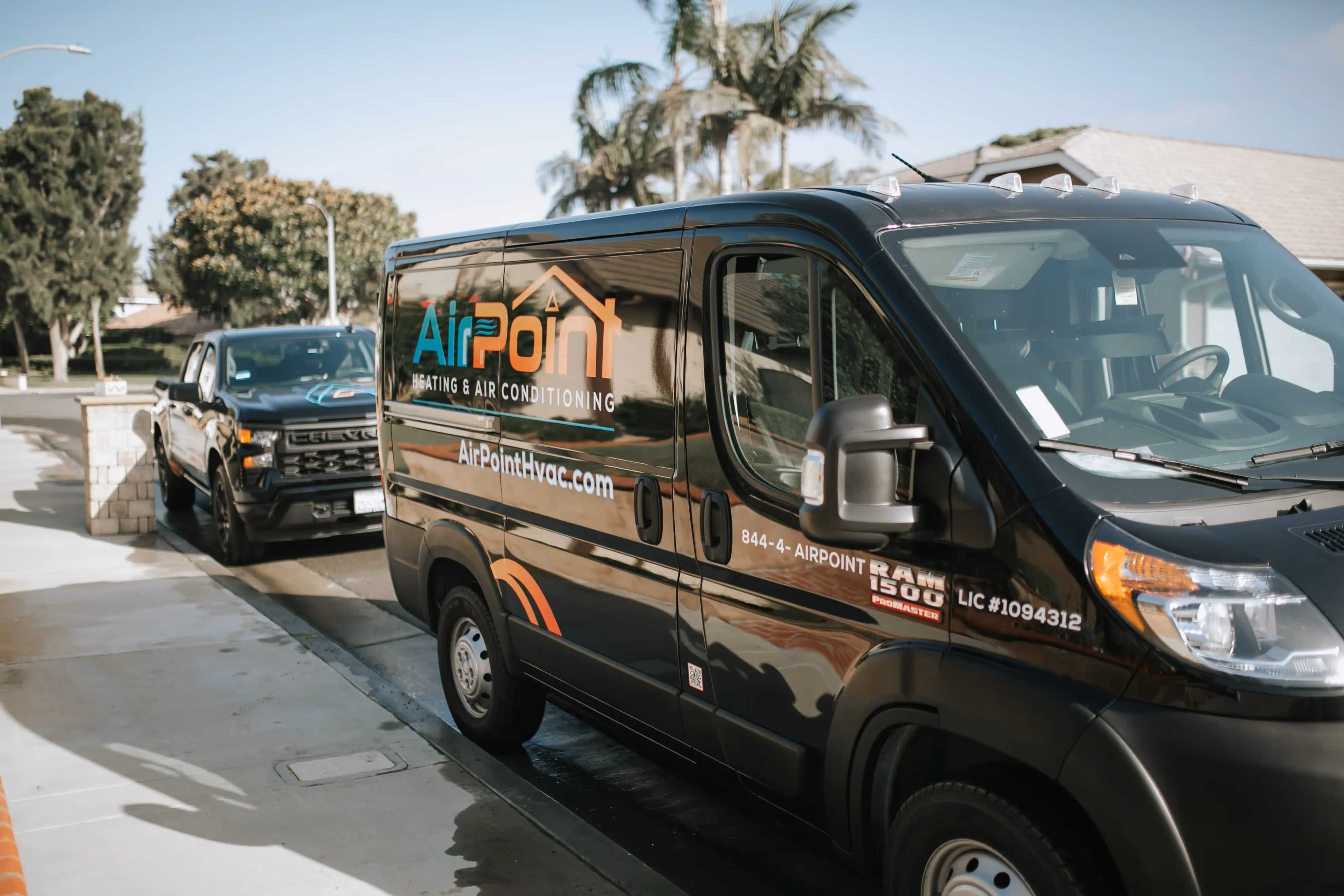 Black AirPoint HVAC service van parked on street with palm trees