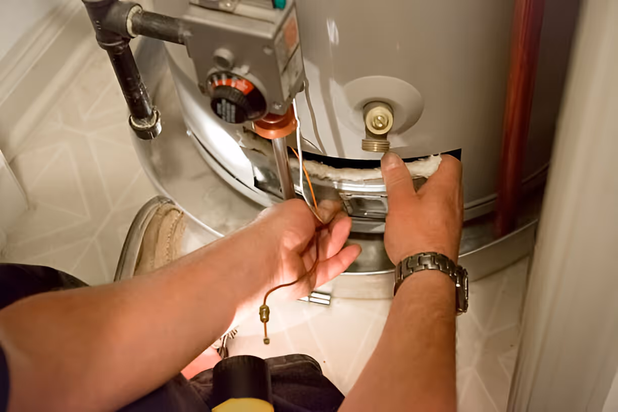 Hands repairing water heater, using tools and adjusting internal components