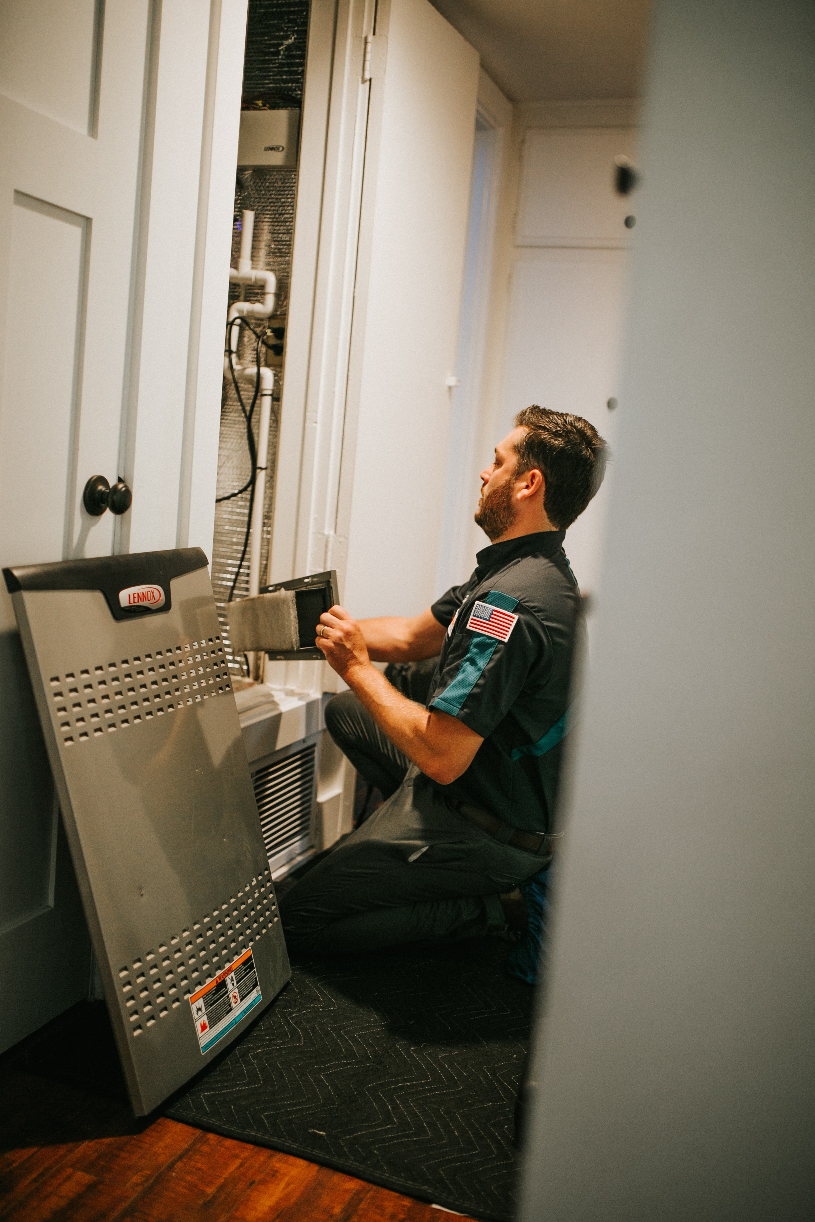 Technician checking HVAC system in utility closet with Lennox equipment