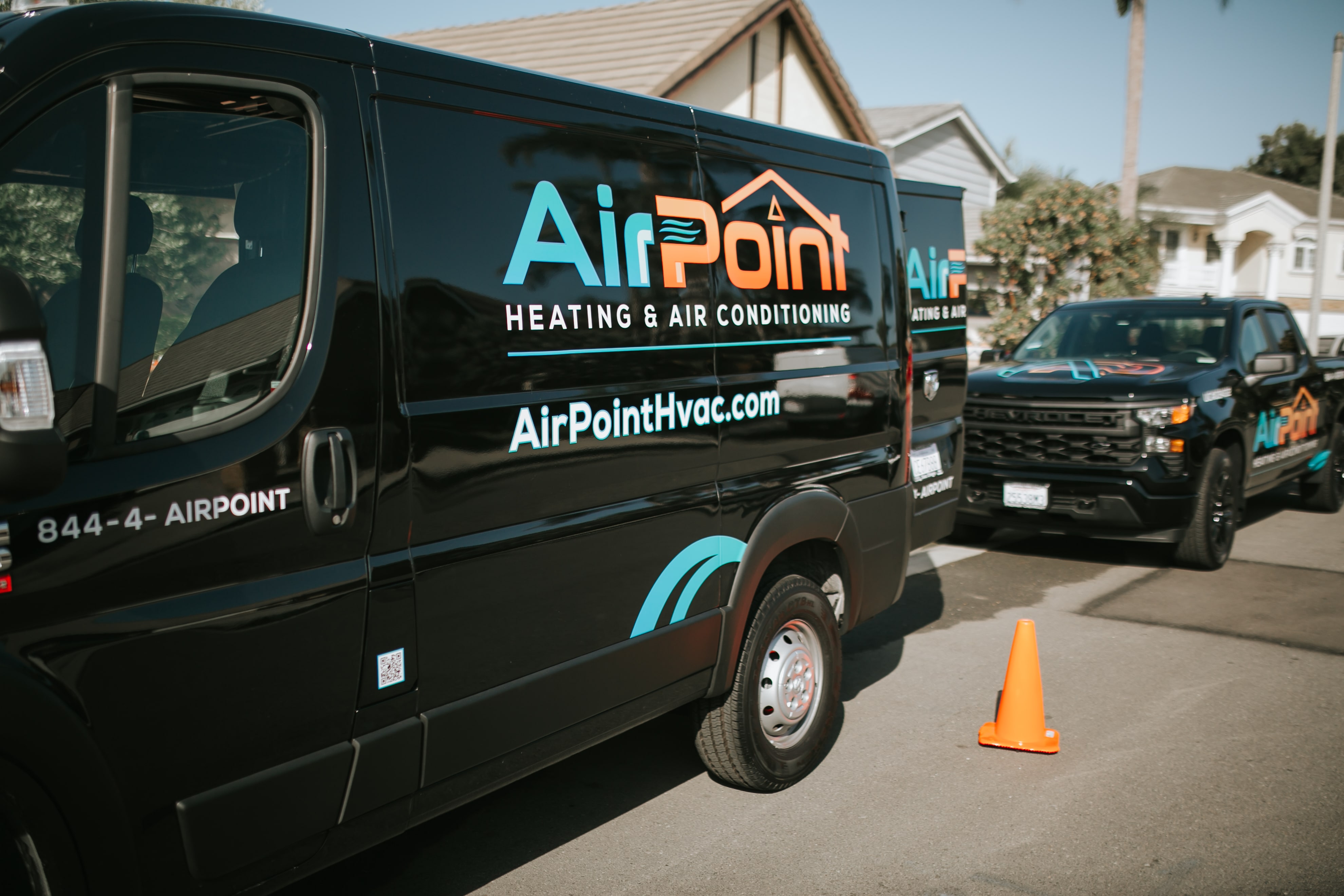 Black AirPoint HVAC service van parked on street with orange traffic cone