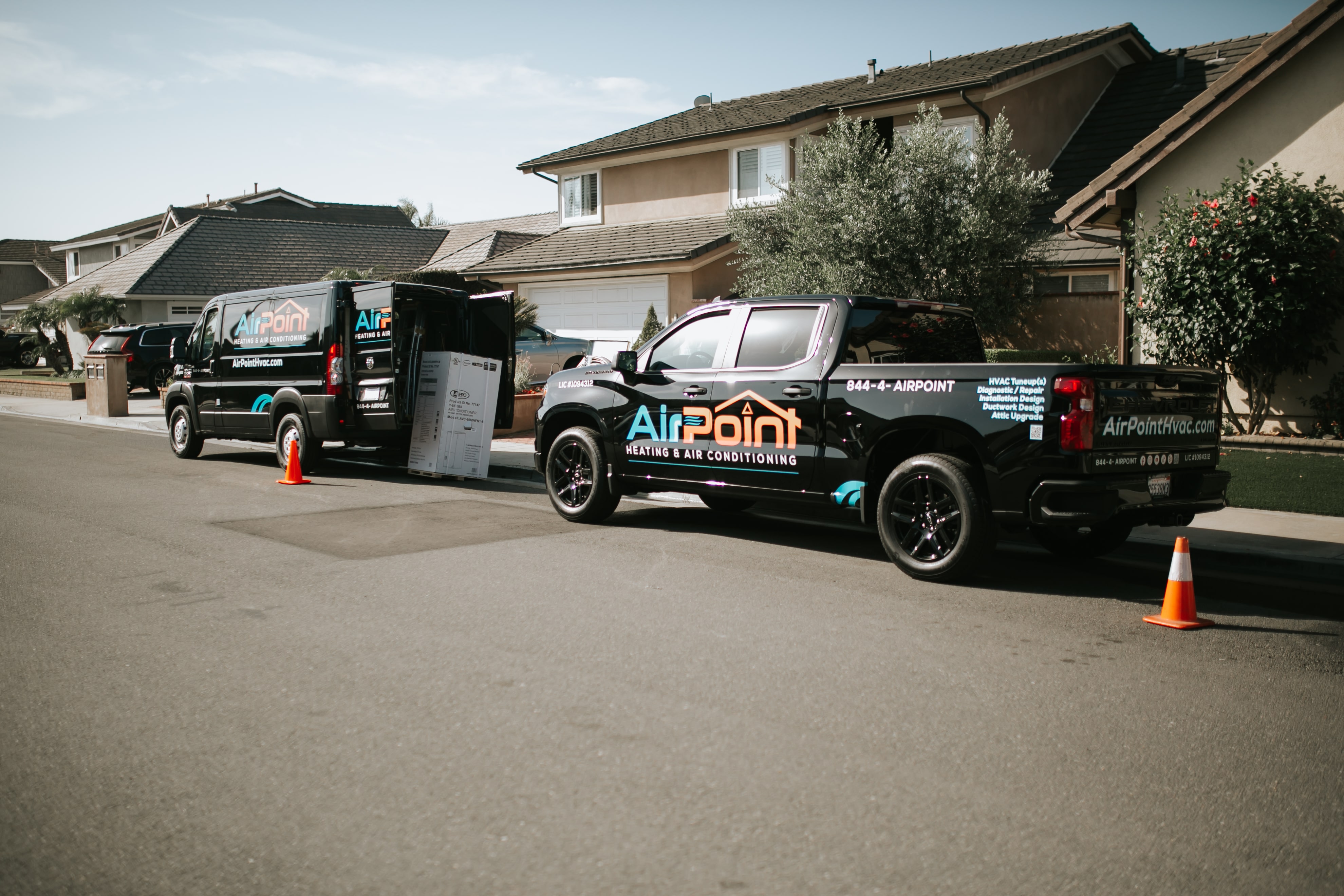 AirPoint HVAC service vehicles parked on suburban street with orange cones
