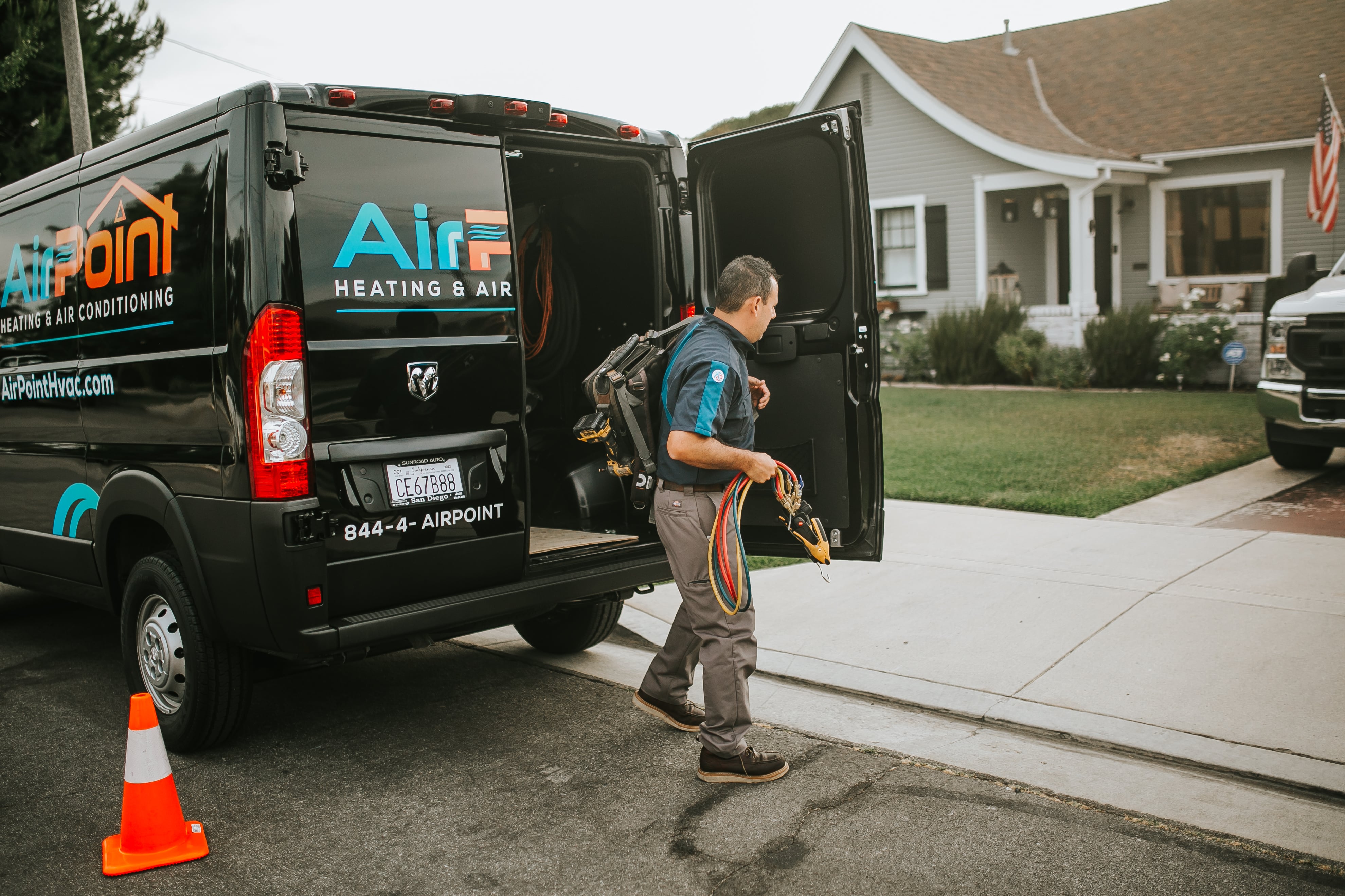 HVAC technician with equipment near service van in residential neighborhood
