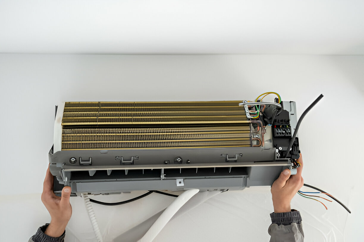 Hands installing or repairing an air conditioning unit's internal components