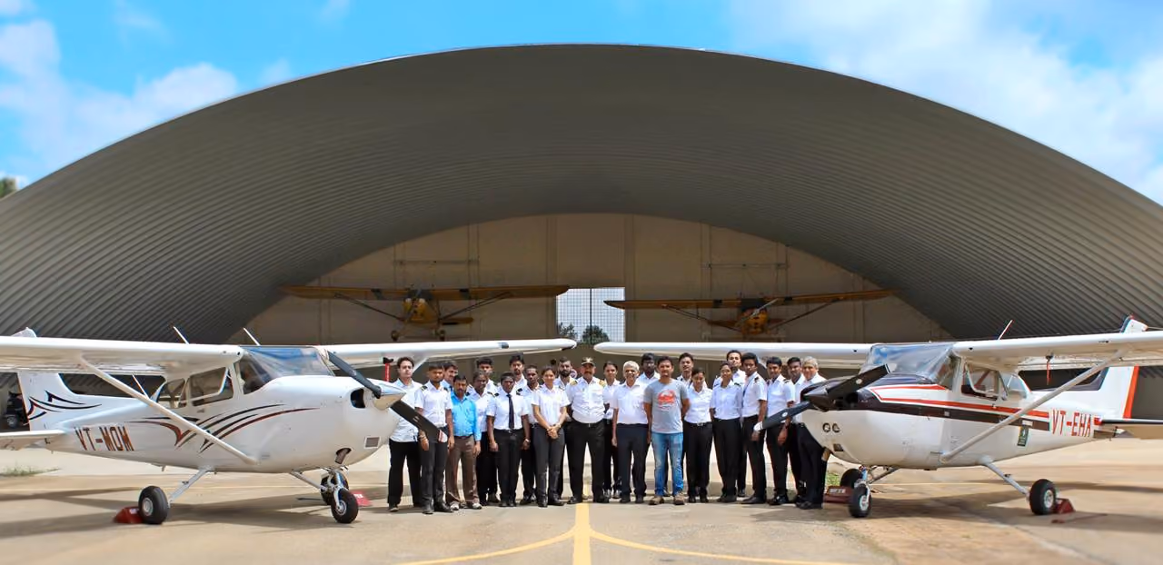 Group and planes before arched hangar in Govt Flying School