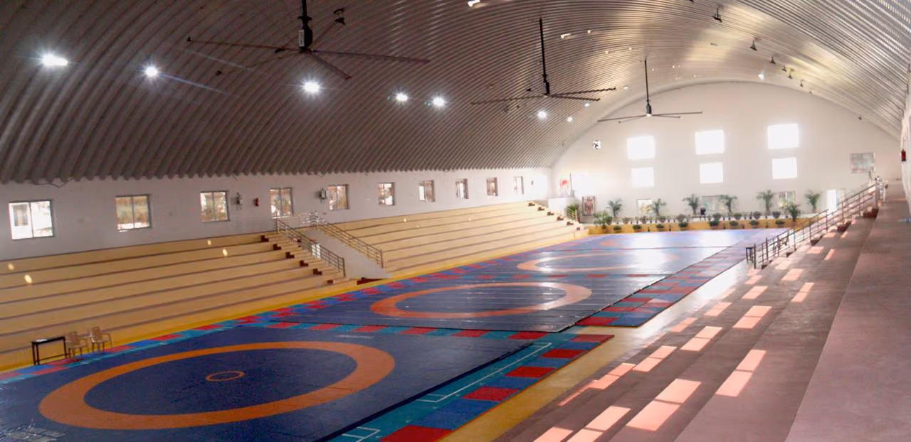 Indoor wrestling arena with arched roof and colorful mats