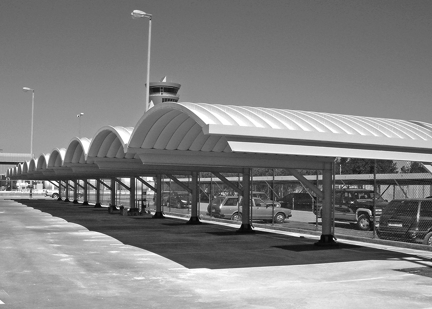 Arched cantilever parking shelters with vehicles underneath