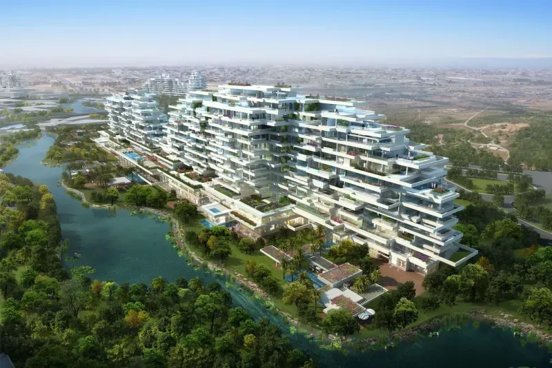 Large modern tiered residential complex surrounded by lush greenery and adjacent to a winding river.